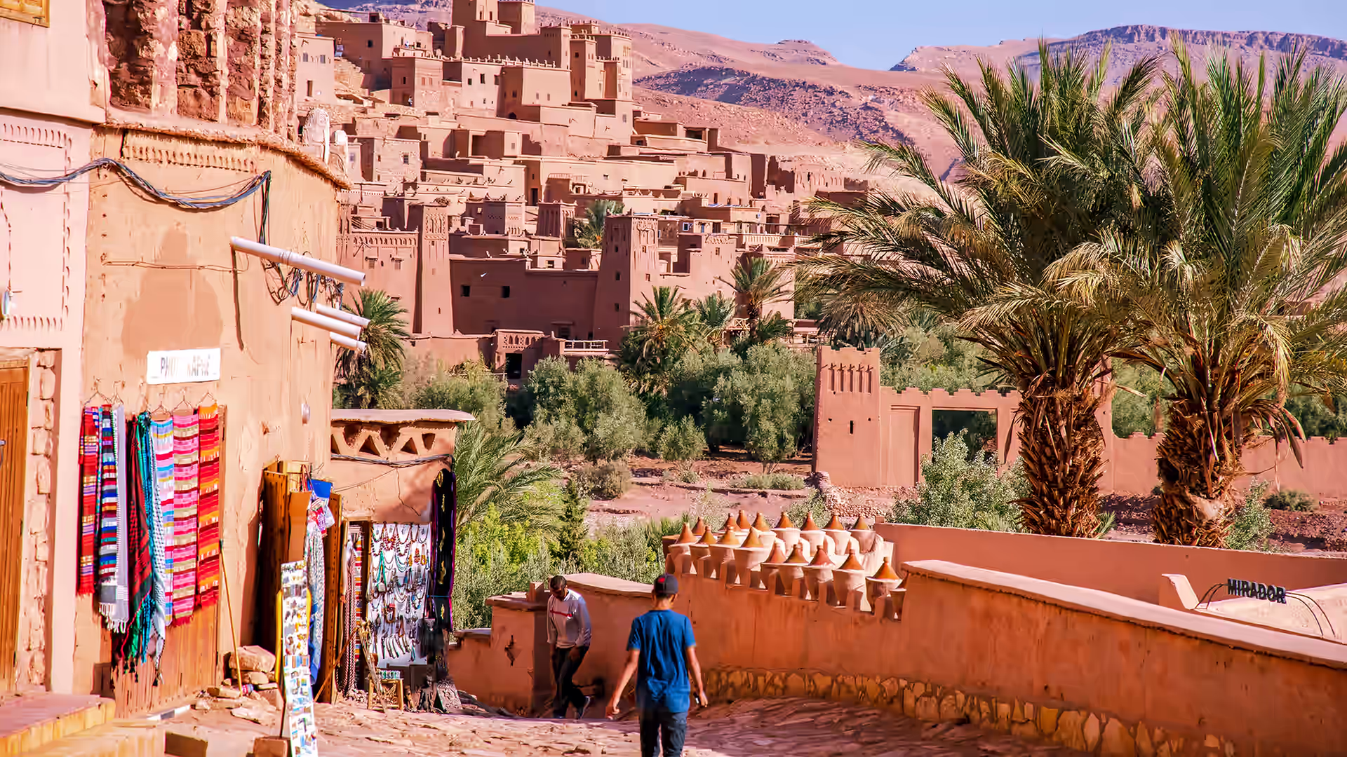 Lane of craft stalls and palms below the earthen towers of Aït Benhaddou