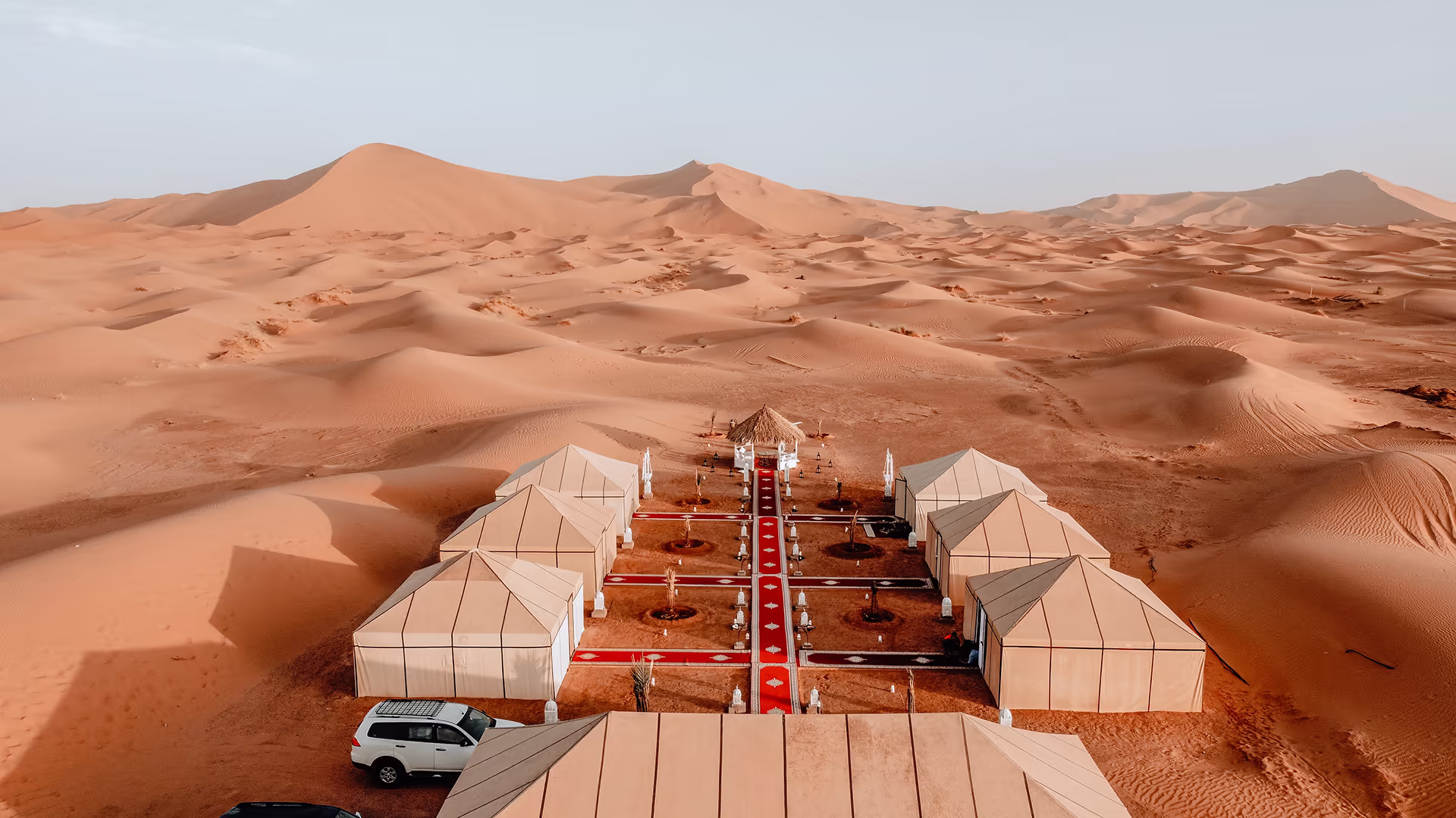 Desert camp in the Moroccan Sahara with the dunes behind it at dusk