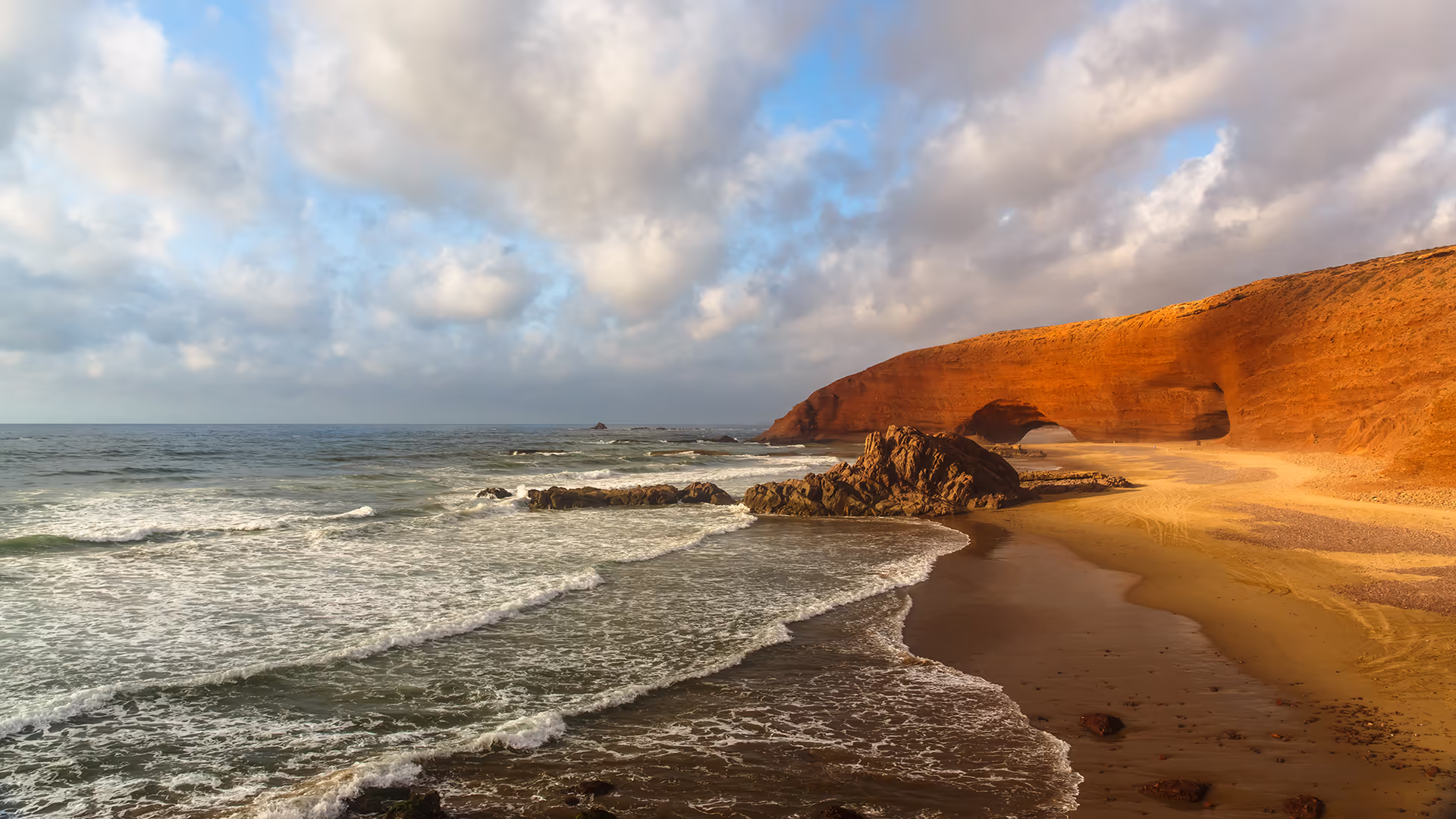 Red rock arch on Legzira beach with the Atlantic behind it at sunset