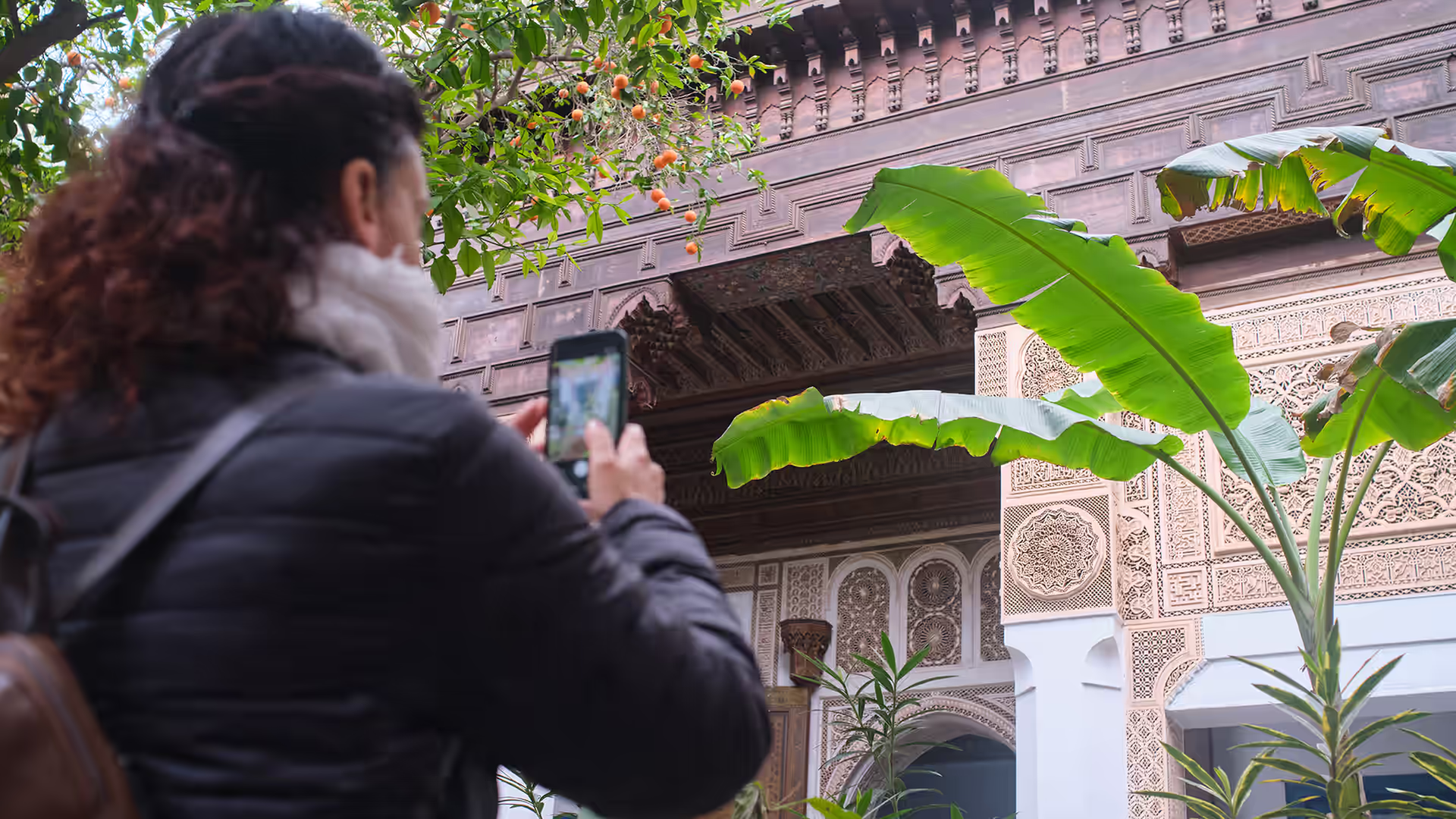 Planted courtyard garden inside a Marrakech riad with a visitor taking a photo