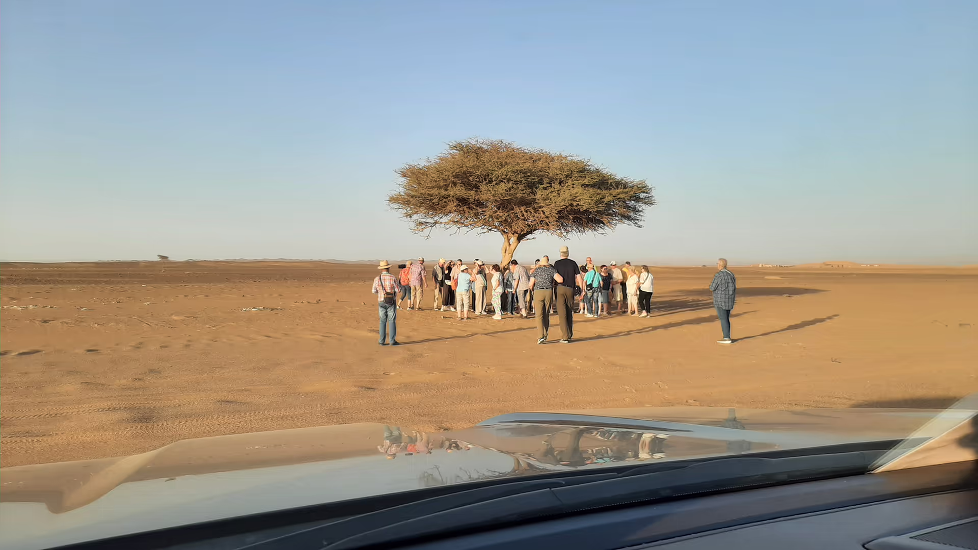 Small group walking over a dune ridge towards the setting sun in the Sahara