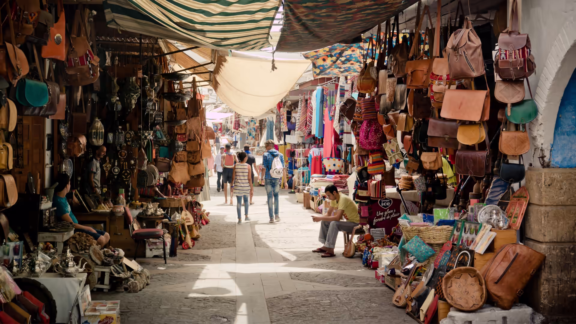 Covered souk alley hung with leather bags, lanterns and baskets