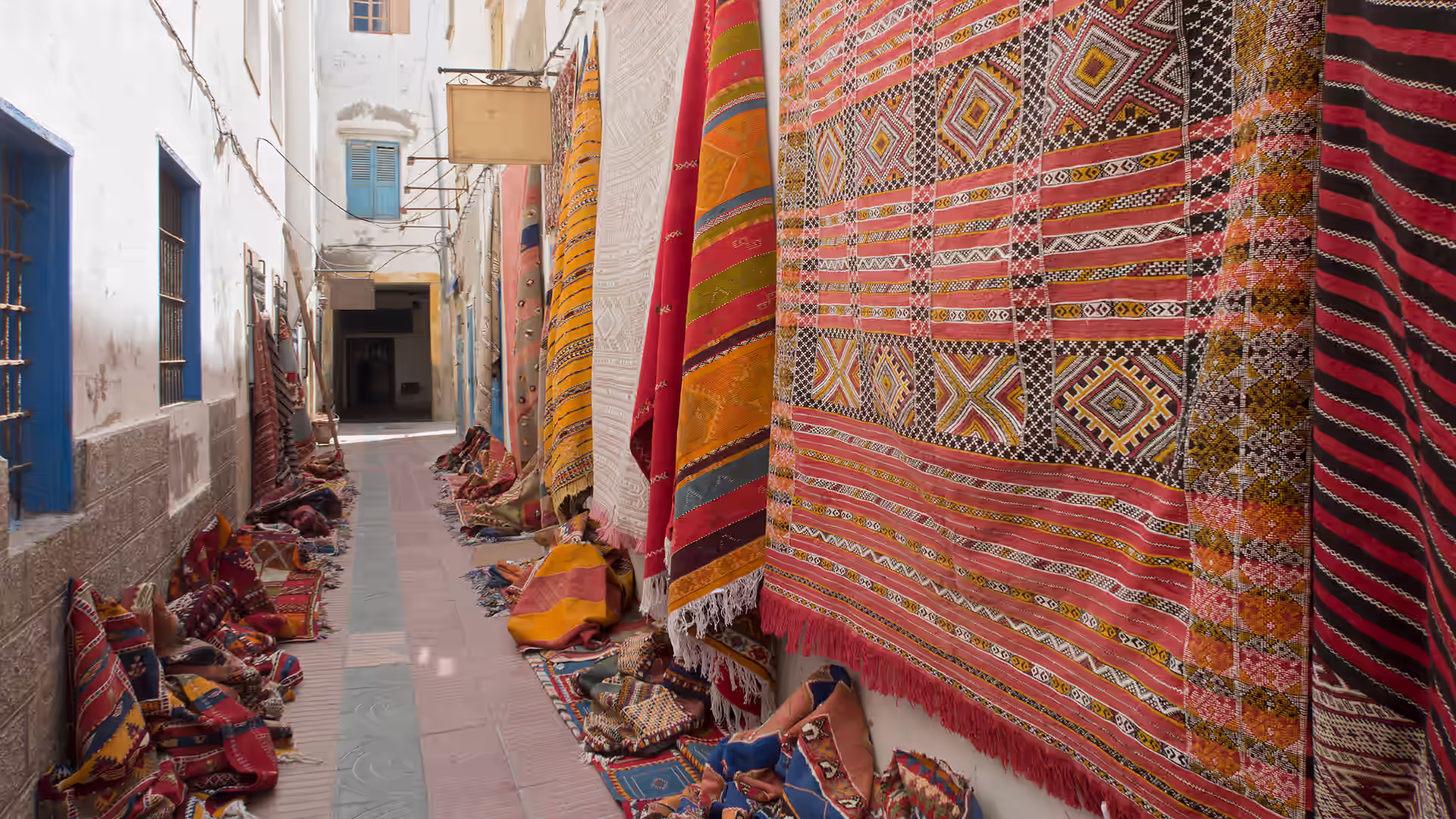 Traditional Moroccan carpets hung in rows outside a carpet shop